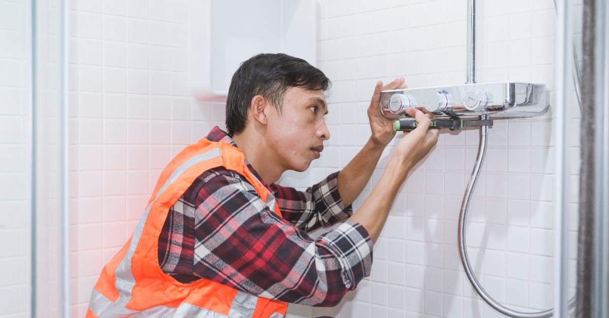 plumber in high vis jacket fixing a shower uk